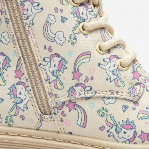 Fillette portant des bottes beige à motifs licornes, style hivernal mignon avec robe rose et chaussettes chaudes.