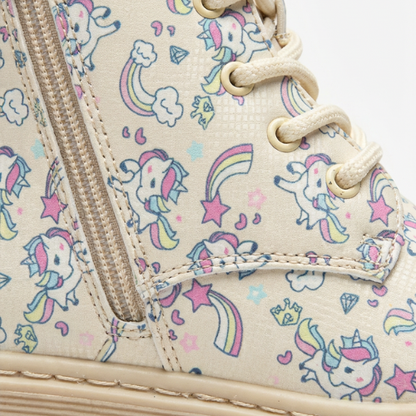 Fillette portant des bottes beige à motifs licornes, style hivernal mignon avec robe rose et chaussettes chaudes.