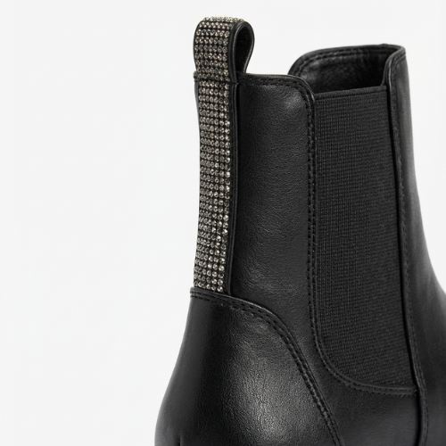 Enfant portant des bottes Chelsea noires à semelle épaisse et détails brillants à l’arrière, look hiver chaud.